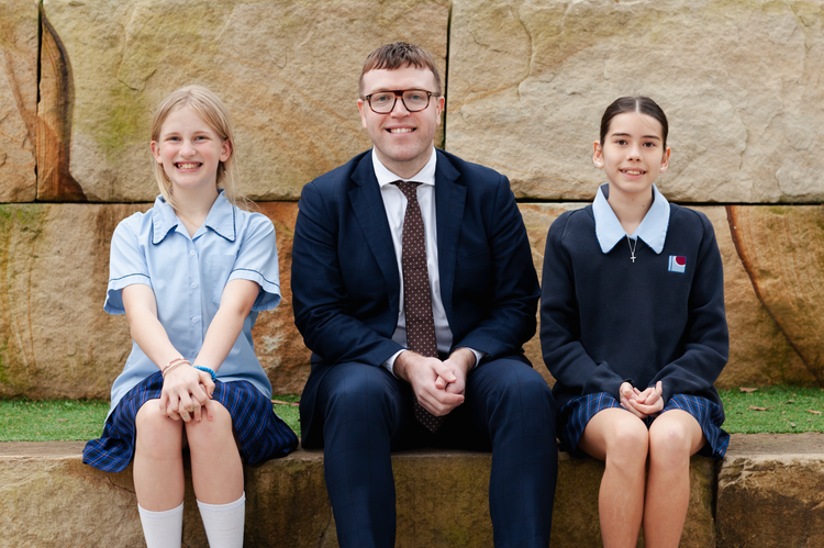 Students sitting with teacher outisde